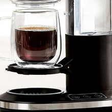 Single-serve coffee maker dispensing into a glass mug with dark coffee