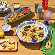 Round serve bowl with blue fish pattern filled with spaghetti and mussels