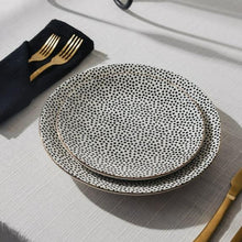 Stoneware dinner plates with black dotted medallion pattern, stacked