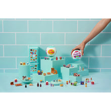 Mini fridge playset with hand inserting a capsule and miniature groceries on shelves