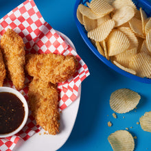 Potato chips with dipping sauce on a plate beside a bowl of chips