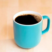 Blue mug filled with dark coffee with frothy crema on top