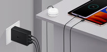 Black 65W adapter plugged into wall powering devices via connected cables