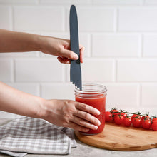 Canning utensil with serrated edge and blue handle placed on a jar