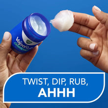 Vicks VapoRub ointment jar and hand applying white rub on fingertips