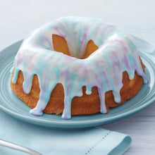 Bundt cake with pastel icing drips on a light blue plate