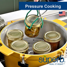 Wide-mouth glass canning jars with gold-tone lids inside a pressure canner