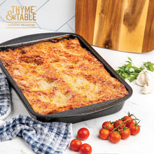 Black nonstick lasagna pan filled with baked casserole, rectangular deep shape