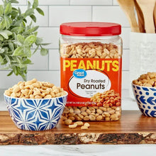 Jar of dry roasted peanuts with orange label and red cap, with peanuts in bowl nearby.