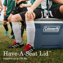 Hard-sided cooler in lakeside blue with Coleman badge, standing on grass outdoors