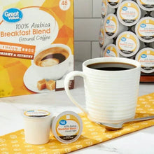 Ground coffee pods with cup and creamer beside 100% Arabica Breakfast Blend box