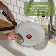 Black ceramic non-stick sauté pan rinsed at sink with red base indicator