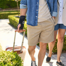 Black wrist brace worn on a hand holding a rolling suitcase handle