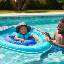 Baby smiling in blue baby pool float with canopy while held in shallow water