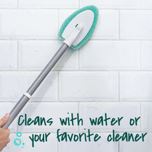 Extendable scrubber with green pad against white tile wall
