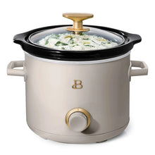 Porcini taupe manual slow cooker with black lid, gold knob, filled with creamy dish