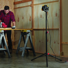 Tripod stand holding a square work light, black frame with red locking parts