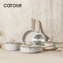Nonstick cookware set with pots and pans, glass lids, and light wood handles.