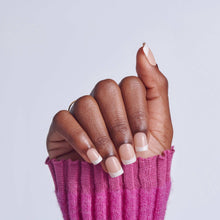 Short white French-tip press-on nails on hand with pink knit sleeve