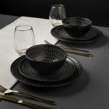 Black stoneware dinnerware set on table: plates and bowls with ridged pattern