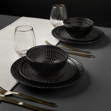 Stoneware dinnerware set with black bowls and plates, plus gold-tone utensils