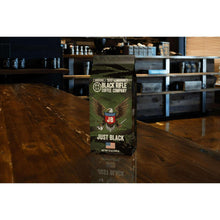 Black Rifle Coffee Company Just Black ground coffee bag, medium roast, on wooden counter