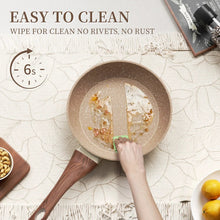Nonstick frying pan with speckled brown interior being wiped with cloth, wood handle