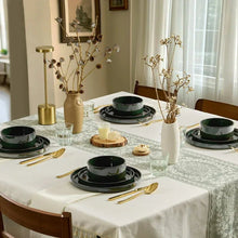 Ceramic dinnerware set with dark green bowls and plates arranged on table