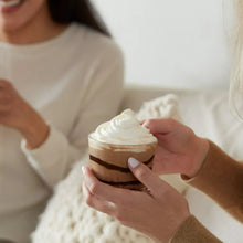Person holding a small whipped-cream topped dessert cup