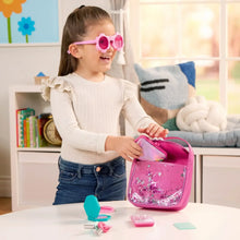 Pink glitter toy purse set with sunglasses and play accessories held by a child