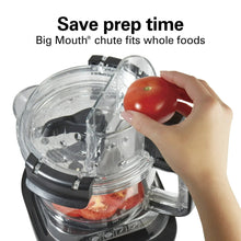 Clear food processor lid with large feed chute as a hand places a tomato inside