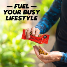 Hands holding a red no-shell pistachios snack bag with a few pistachios