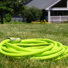Coiled lime-green garden hose on grass with gray end fittings visible