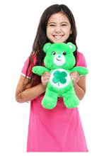 Green plush teddy bear held upright with clover belly patch