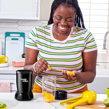 Black personal blender with clear cup, to-go lid, and yellow ingredient being blended