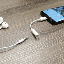 White USB-C to 3.5 mm adapter cable connecting to a phone and AUX device