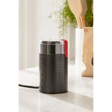 Black electric coffee grinder with stainless lid, textured sides, red switch and power cord