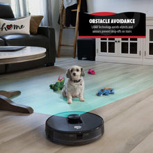 Black robot vacuum on hardwood floor near seated dog and toys