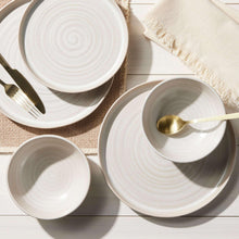 Stoneware dinnerware set with swirl pattern plates and bowls, styled with utensils