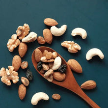 Cashews scattered around a wooden scoop, whole nut pieces visible