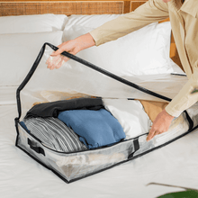 Clear storage bag with handles and zipper, holding folded clothes inside