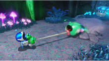 Robot character holding a glowing green device and cable near other robots in a cave