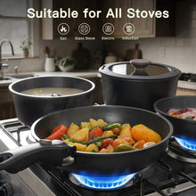 Black nonstick pans on a gas stove, food simmering in multiple cookware pieces