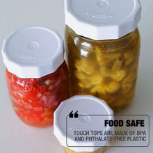 White tough-top canning jar lids on food jars, with one lid in foreground