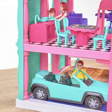 Pink 3-story dollhouse play set with teal and purple furniture, dolls, and car