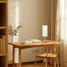 Touch table lamp with cream fabric shade and wood base on a wooden desk
