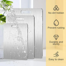 Brushed titanium cutting boards with curved handle cutouts, shown with water droplets