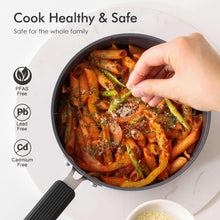 Dark gray saucepan with vegetables being stirred by hand
