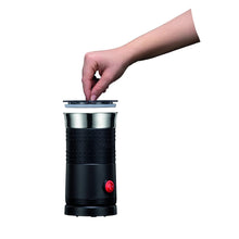 Black electric milk frother with cap removed, showing stainless cup