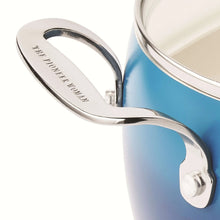 Stainless steel pot handle on a denim blue ceramic non-stick pot with glass lid